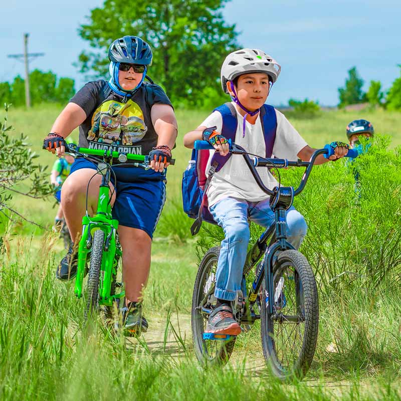 Kids riding on a flat trail with long grass